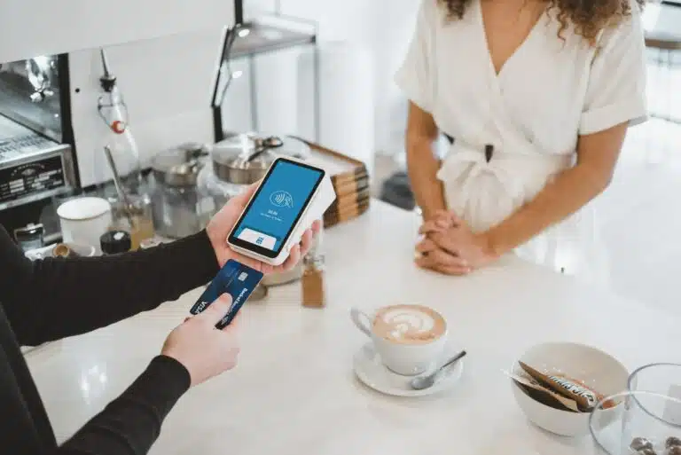 woman standing and holding smartphones linking credit card to phone, PCI P2PE related